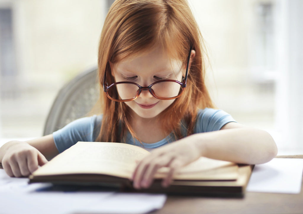 a child wearing glasses reading a book