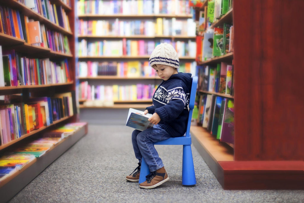 young boy reading in the library