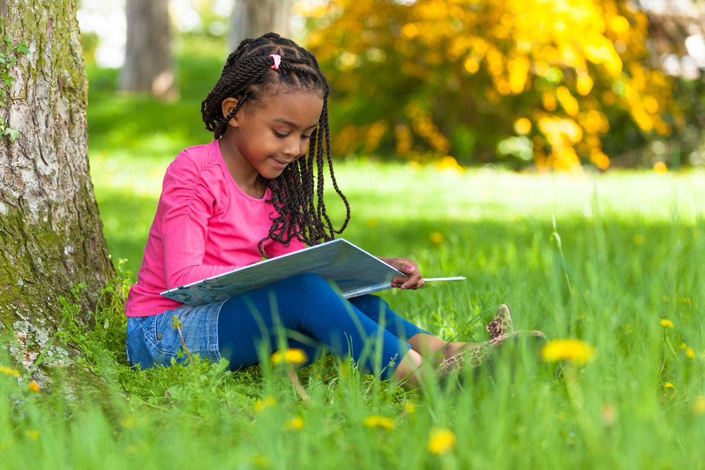 young girl reading a book outside
